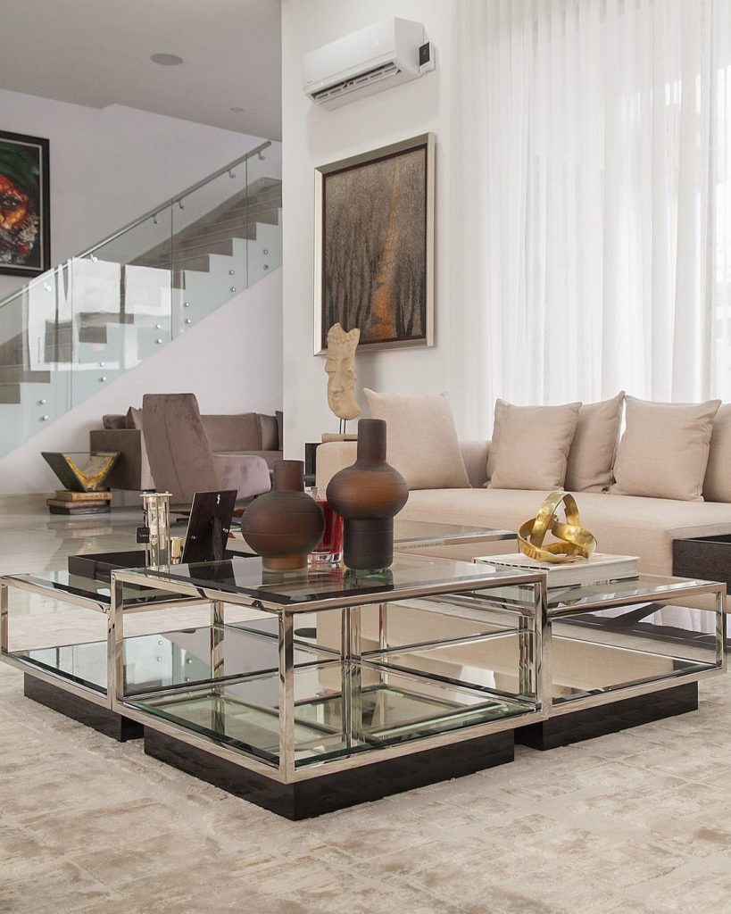 Light coloured sectional sofa with eichholtz glass coffee table in ikoyi home by Urban Living