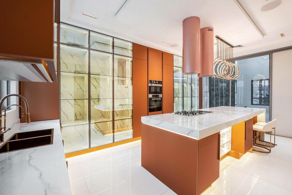 A view of the kitchen showing the combination of  rose gold and burnt orange cabinets designed by Rome signature.